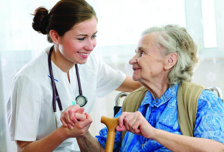 A young nurse holding hands with a senior woman.